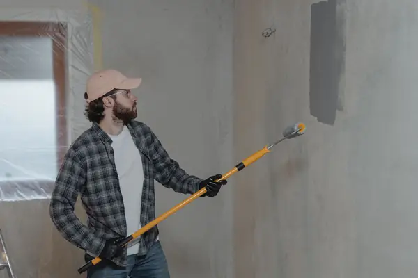 Painter rolling grey paint onto an interior wall in Little Rock